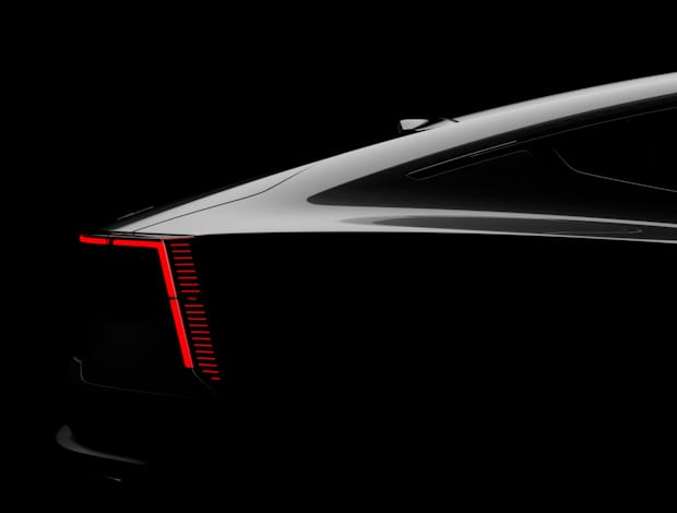 Rear view of Polestar car with illuminated red tail light against black background.